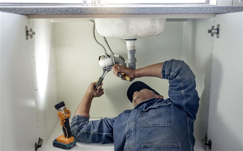Plumber repairing kitchen sink drain pipes in Jupiter, Florida